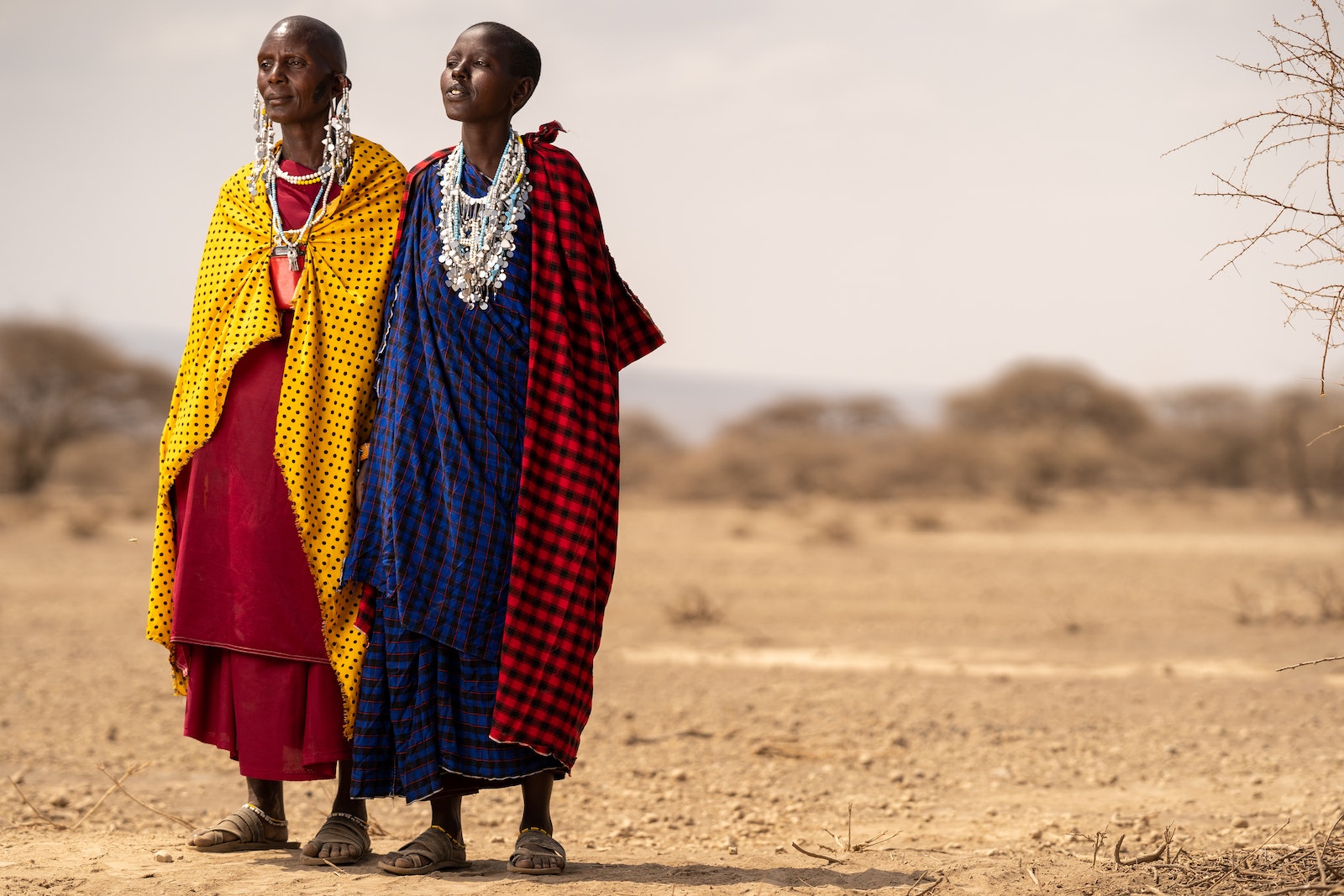 People Wearing Checkered Tribal Clothes Standing on the Desert