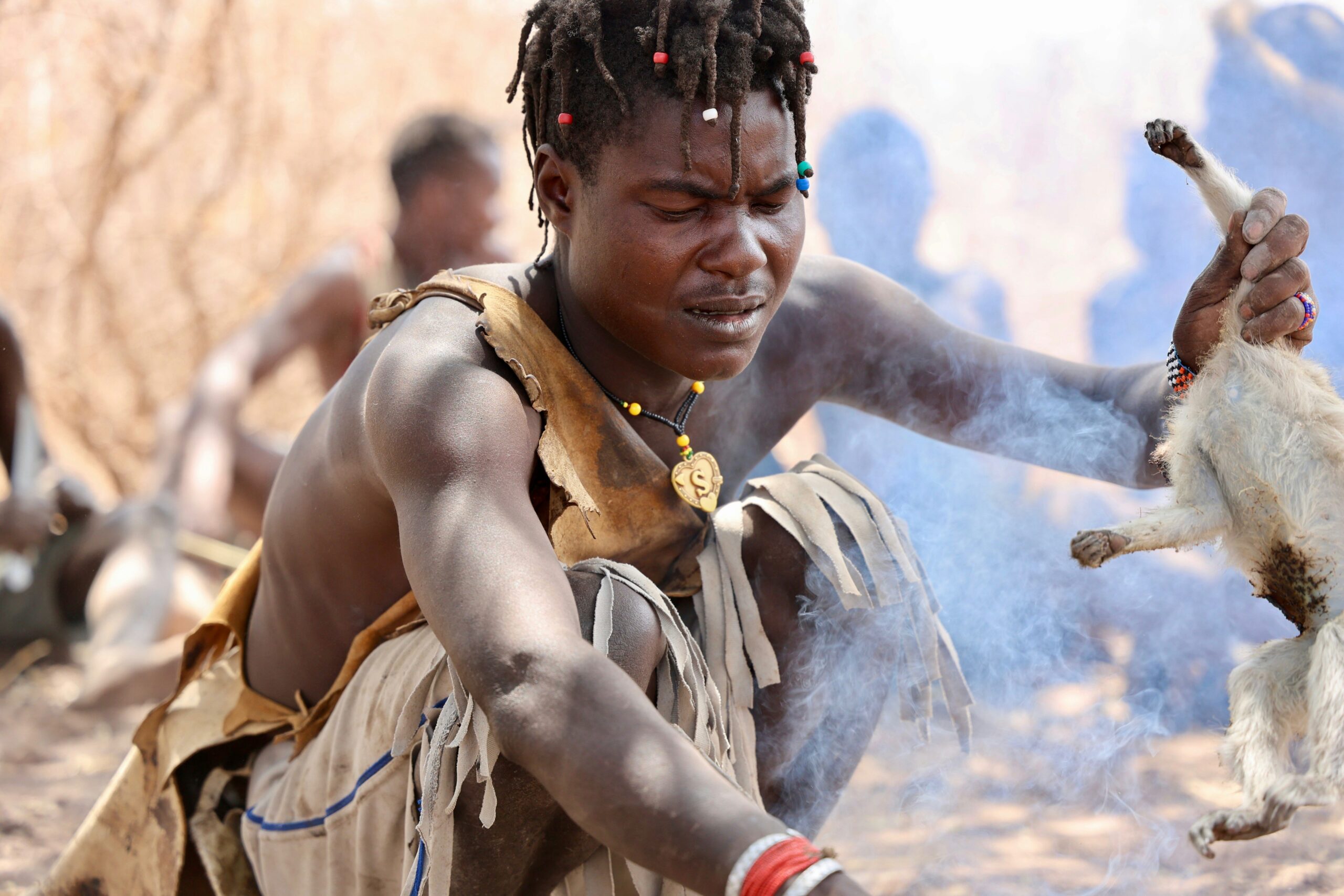 young hadzabe man cooking a monkey for lunch